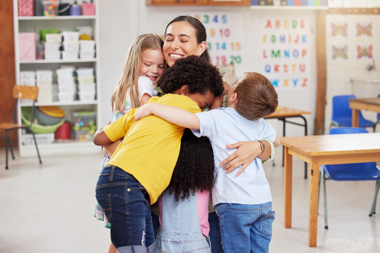 young students hugging their teacher