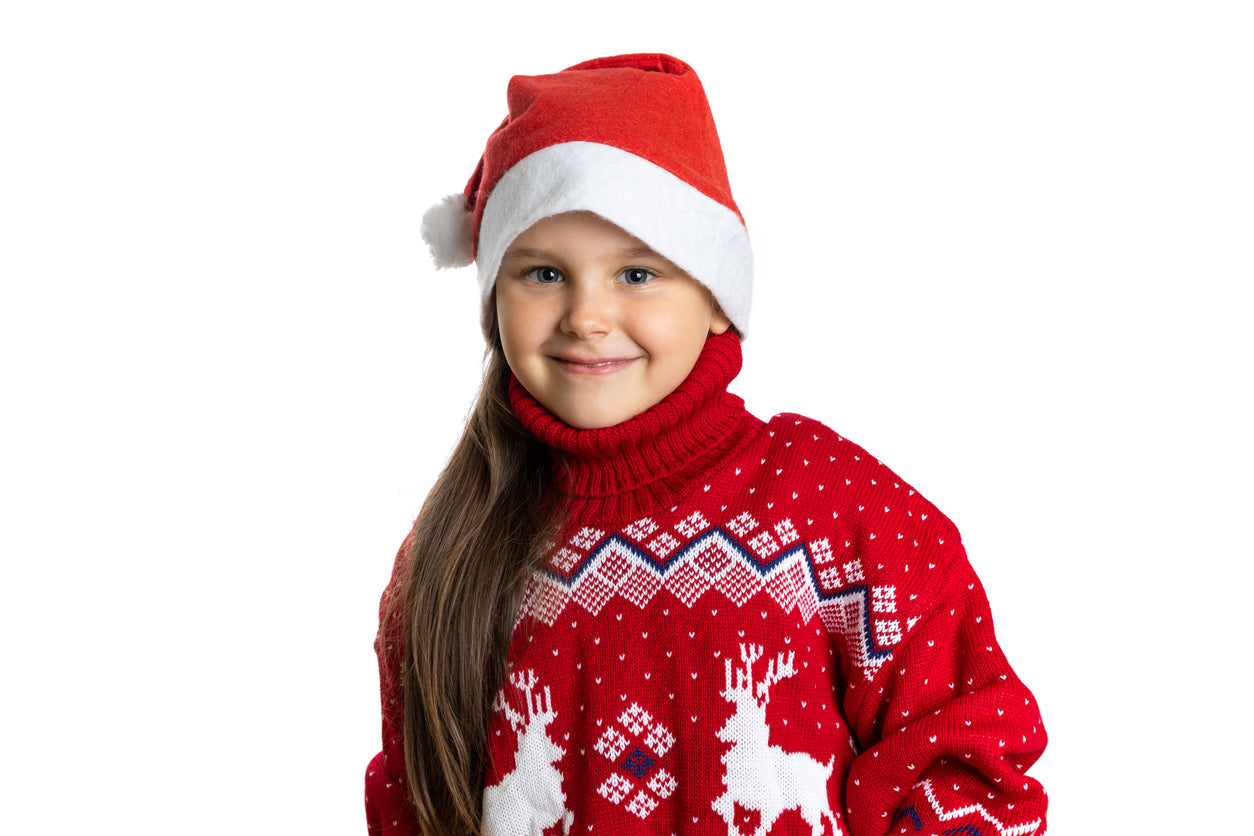 young girl in a red christmas sweater and santa hat