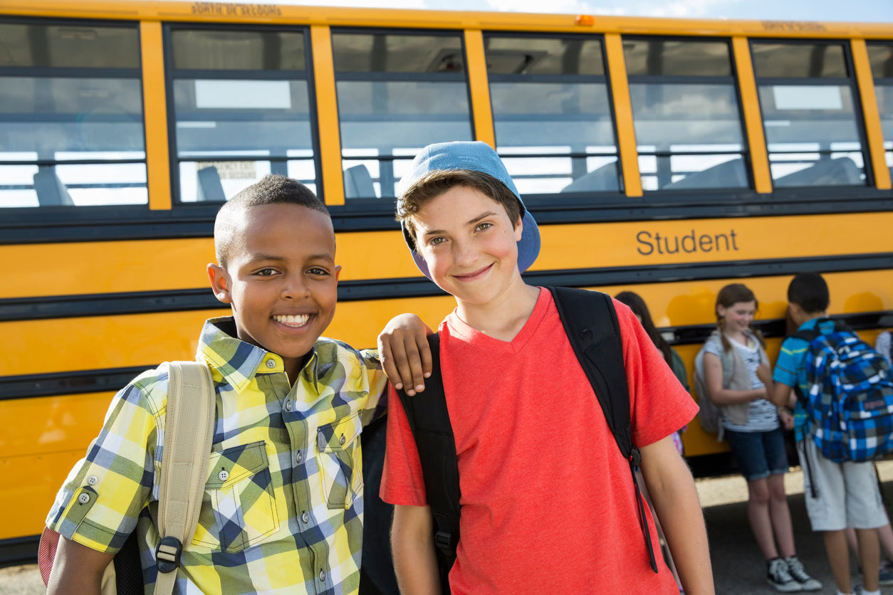 2 elementary school boys standing by a school bus for a field trip