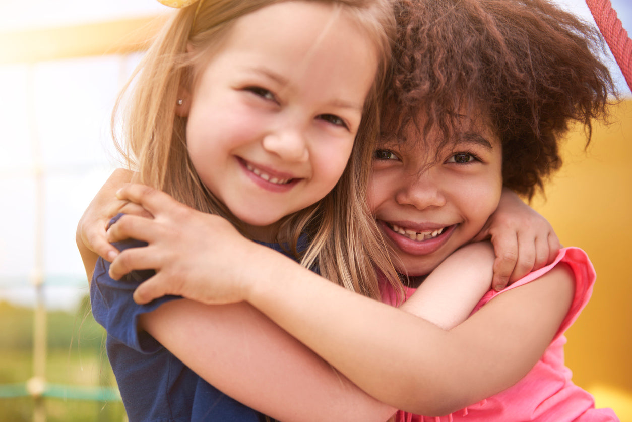 2 little girls smiling and hugging each other